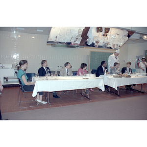 Panel seated at tables listen to a chef speak