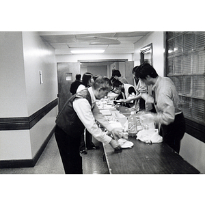 People get food from a buffet table at a Thanksgiving dinner celebration