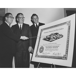 Three men examine a Land Share certificate