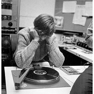 Young man staring at turntable in the broadcast booth at the WNEU studio