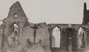 Close-up view of a crucifix and empty stained-glass windows on the side of a destroyed stone building, Ypres, 1919