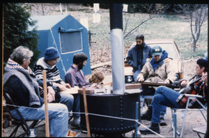 Protesters near the home of war tax resisters Randy Kehler and Betsy Corner, seated outside around a wood stove