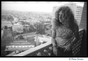 Robert Plant (Led Zeppelin) on the balcony of his room at the Riot House, with billboard in the background advertizing the new album, Physical Graffiti