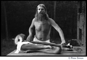 Bhagavan Das: full-length portrait seated in a lotus pose next to a Siamese cat, holding an dotara, next to a Siamese cat