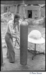 Young woman ringing a cylindrical gong, Lama Foundation