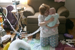 Kim Grant hugs her premature grandchild Teagan after giving her a bath in early morning in their Pawtucket living room as she starts their daily routine