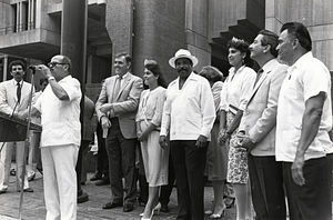 Mayor Raymond L. Flynn outside City Hall wataching unidentified speaker with Alfredo de Jesús and several unidentified Puerto Rican community representatives