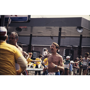 Shirtless man passing YMCA staff at water table at Boston Athletic Association (BAA) marathon