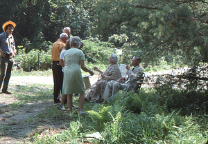 Ella and Arthur Rosenburg (seated on right) greeting friends at Moon Barn Raising at entrance to Hopkins Forest on 2 August 1975. Steven Masters in straw hat at left.