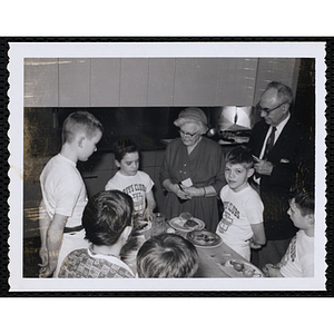 Members of the Tom Pappas Chefs' Club stand around a table in a kitchen