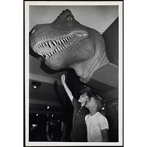 Two boys pose with a tyrannosaurus head at the Museum of Science
