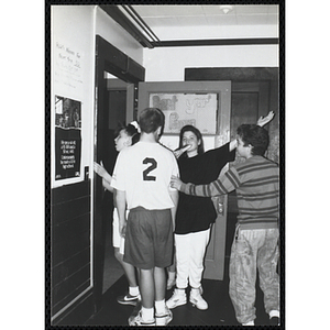 Four children gather by a door for the Tri-Club slide show at the Charlestown Clubhouse