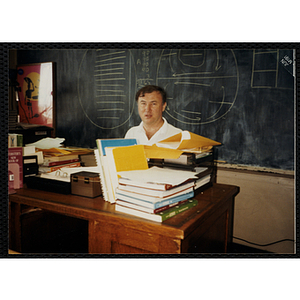 An Unidentified teacher sitting at his desk in a classroom
