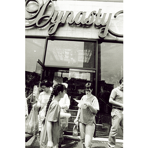 Female protester distributes informational fliers to a group of people as they exit the Dynasty Restaurant during a picketing demonstration