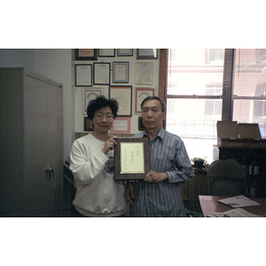 Association members hold a plaque while standing in their office