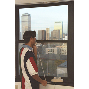 A student looks out of dorm room window while speaking on the phone