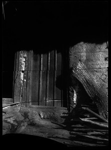 Doorway with plaited mats and stacked wood