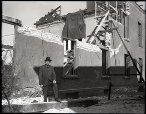 Wilfred H. Booth, standing by wrecked building