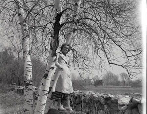 Olivia Fox standing by birch trees and stone wall