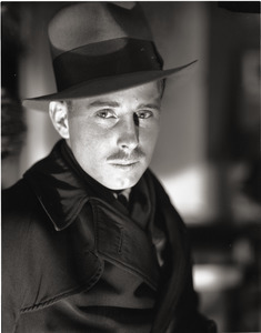 Arthur Hansen, photojournalist: close-up portrait wearing a fedora and trench coat
