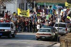 Police car leading anti-war marchers through the streets, led by banner reading 'Bring the troops home now': rally and march against the Iraq War