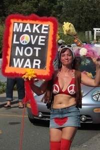 Parade marcher carrying a sign reading 'Make love not war' : Provincetown Carnival parade