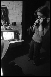 Bonnie Raitt backstage, clasping a rose and watching hockey on television