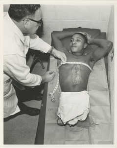 A technician measures a double amputee for a prosthetic fitting