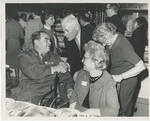 Hermann G. Place shaking hands with veteran in wheelchair at Thanksgiving celebration