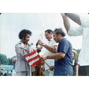 Three men stand with a large trophy at the Festival Puertorriqueño