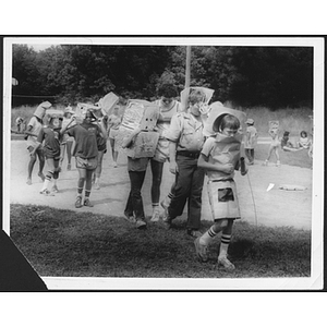 Children carrying boxes along outdoor path