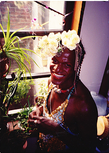 A Photograph of Marsha P. Johnson Standing in a Window with a White Flower Headpiece