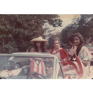 Women sit in the back of a car during a parade for the Festival Puertorriqueño