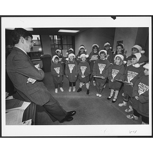 Group of children standing in two lines wearing Santa Claus hats
