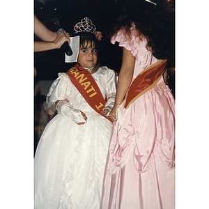 A little girl has a crown placed on her head