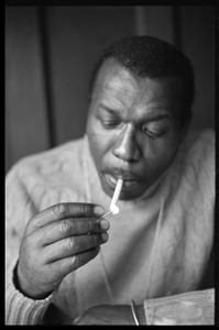 Elvin Jones: half-length portrait of jazz musician, seated, lighting a cigarette