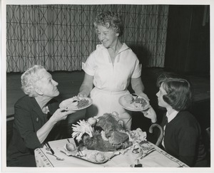 Unidentified woman handing plates to clients