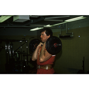 Man lifts a barbell up to his shoulders