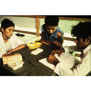 Man and two children sitting at a table with a notebook