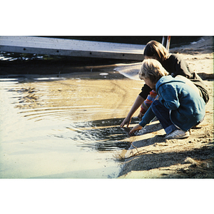 Children touching water on a sandy shore