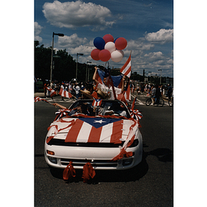 A car covered in Puerto Rican flags drives in the Festival Puertorriqueño parade near Center Street and Columbus Avenue