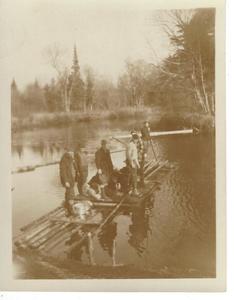 Group of men floating on pond in a wooden raft