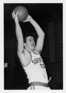 Suffolk University men's basketball player Chris Tsiotos (#33) holds the basketball, 1976