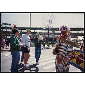 Several staff members, including Jerry Steimel with a megaphone, and Hills Mills Clown Band standing on the street during the Boys and Girls Clubs of Boston 100th Anniversary Celebration Parade