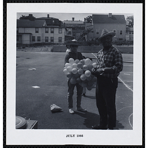 A man holding a bunch of balloons and another man pose for a group shot on Tom Sawyer Day