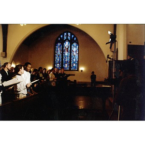 Boston Gay Men's Chorus being filmed while singing in church pews