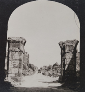 View through an archway of a road lined with damaged stone structures