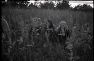 Bill Grabin (center), Julie Howard and unidentified communard crouching in a grassy field