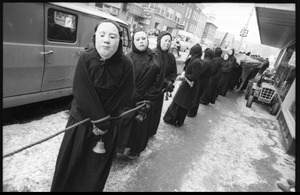 Cloaked and masked protesters (Bread and Puppet Theater) walk through the streets of Montpelier bound by a rope during a demonstration against the invasion of Laos