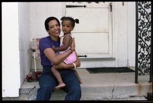 Johnnetta Cole seated on the front steps of a house, holding Zena Allen